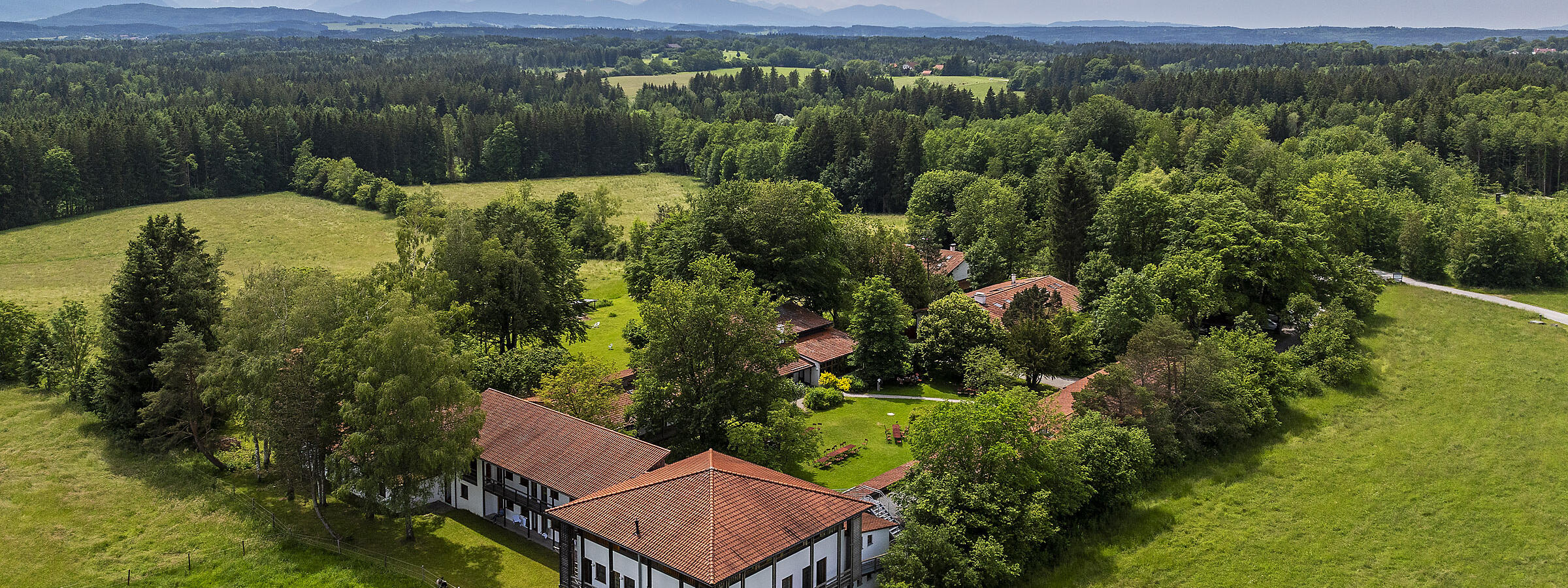 Luftaufnahme des ZIST Seminarhauses, umgeben von grünen Feldern und Wäldern