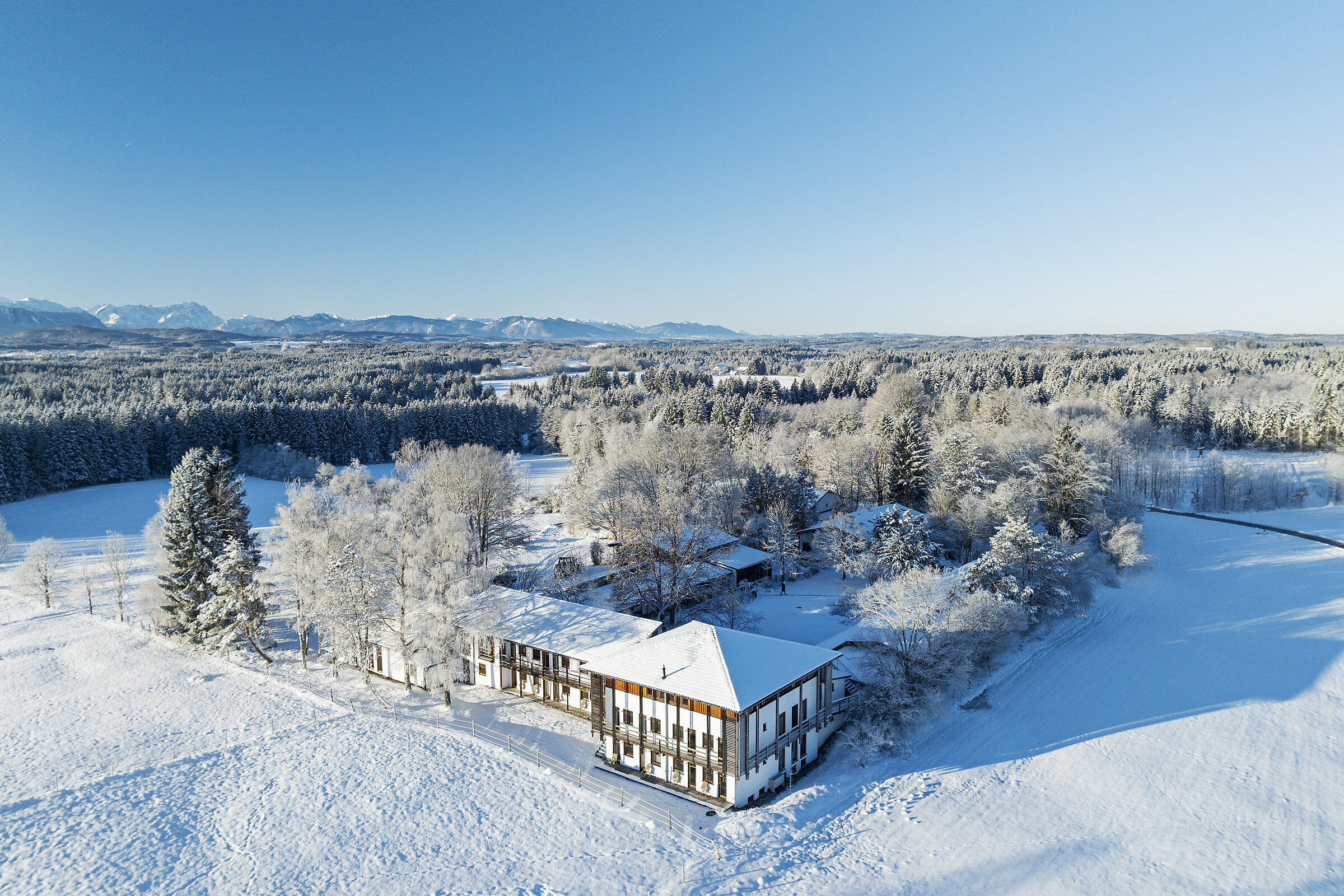 Verschneites ZIST mit Gebäuden und Bäumen in winterliche Landschaft der Voralpen