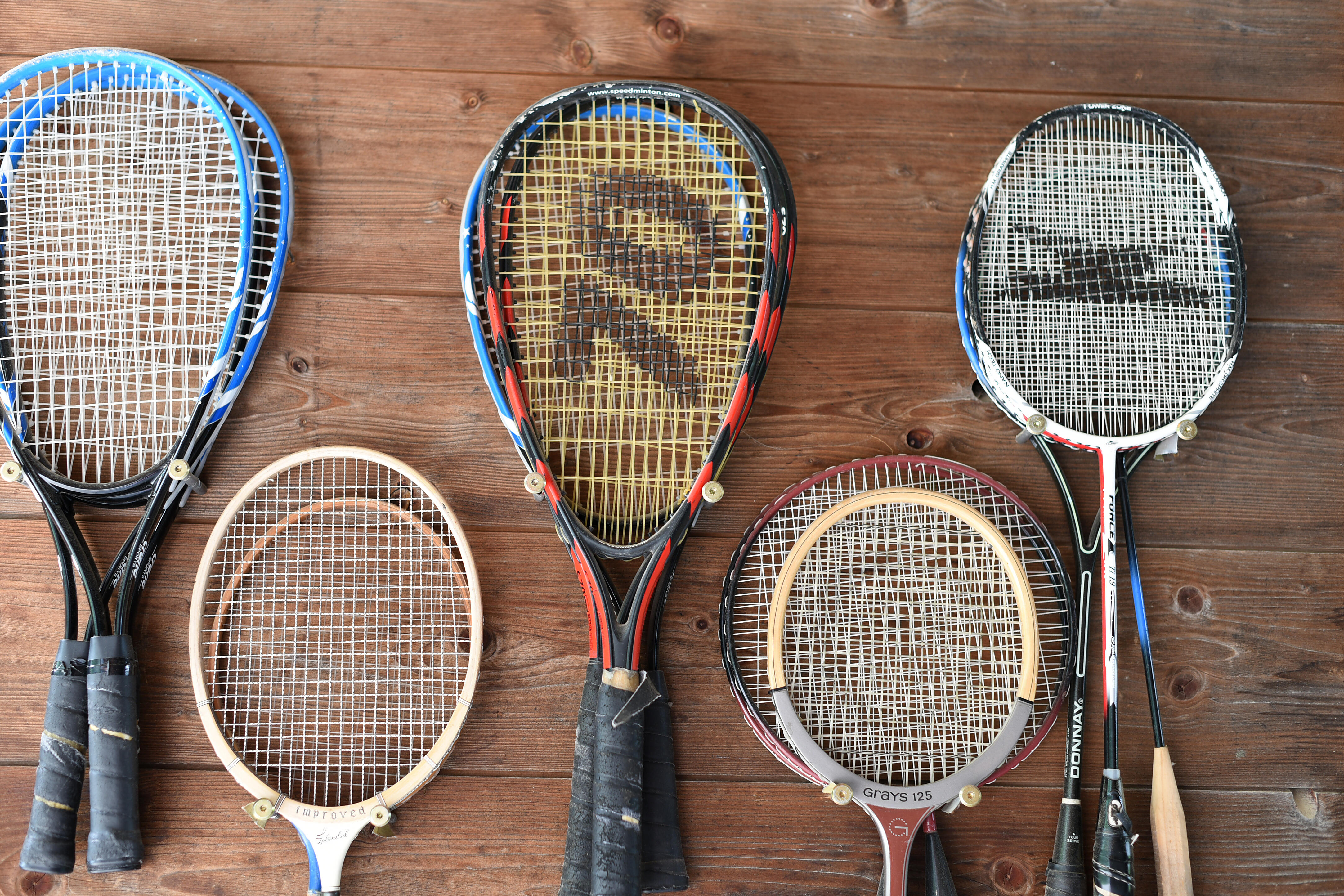 Tennisschläger in verschiedenen Größen und Designs an einer Holzwand in ZIST