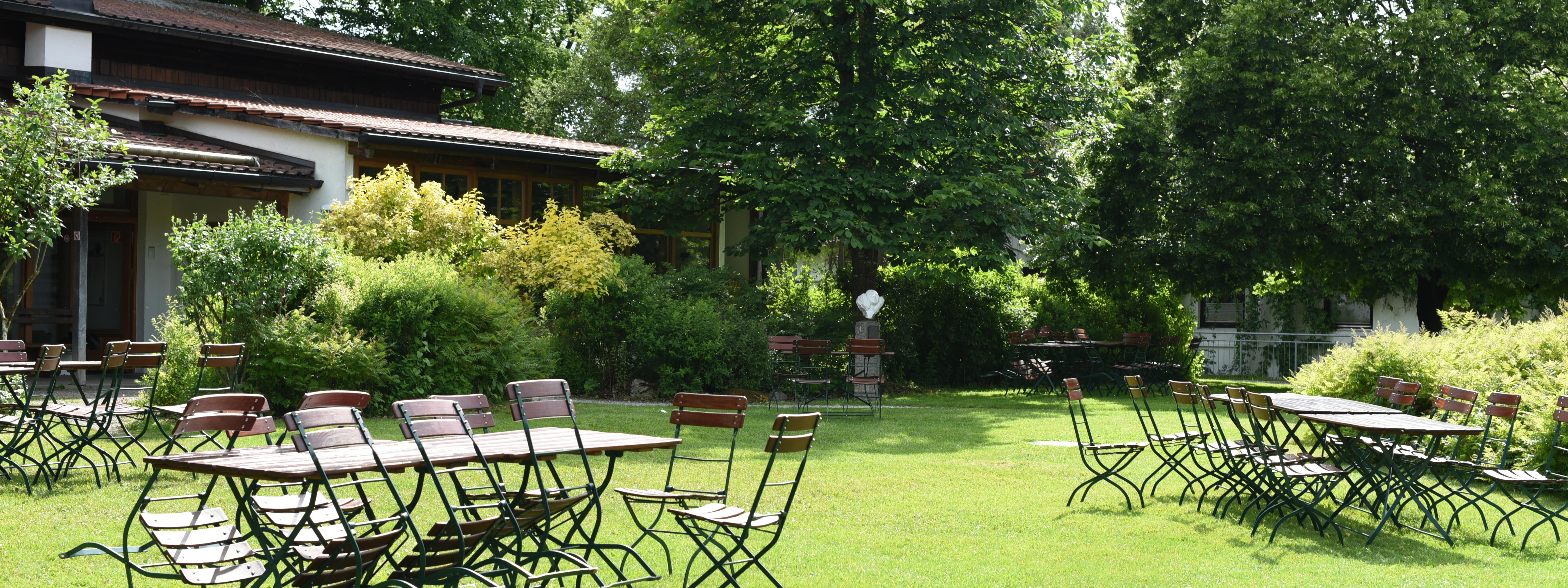 ZIST Garten im Sommer, Stühle sind gegen einen Gartentisch gelehnt.